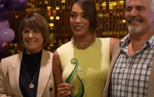 Mila Reuelu-Buchanan holding a green glass award, standing between two supporters at the Stars Awards Night in Karaka. Ask ChatGPT