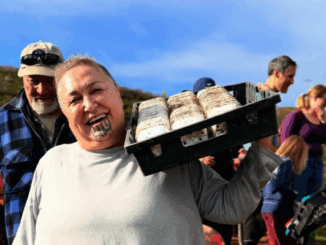 Hikitia Ropata smiling and carrying a tray of seedlings at the Whitireia Park restoration planting event.