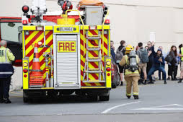 Firefighter walking toward group of evacuees outside North City Mall as fire engine is parked nearby