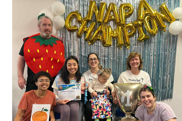 Group of therapists and a child posing under “NAPA Champion” balloons at a paediatric therapy event in Porirua, New Zealand