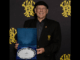 Denys Latham holding WRFU Lifetime Contribution Award in front of Wellington Rugby backdrop.