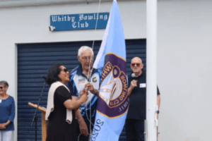Barbara Edmonds and Tere French raise the Whitby Bowling Club jubilee flag during the 50th anniversary celebrations.