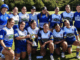Norths Women's rugby team posing with the Eleanor Roosevelt Cup on a rugby field after their tournament win.