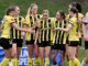 Wellington Phoenix players in yellow-and-black kits celebrate together after scoring during an A-League Women match.