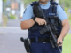 Armed New Zealand police officer holding a rifle at a street scene.