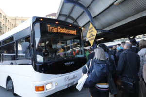 A bus displaying “Train Replacement” picks up commuters at a crowded Wellington station platform.