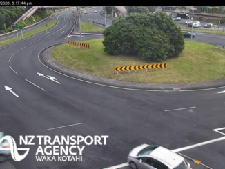 Wide view of a multi-lane roundabout interchange with light traffic and clear road markings.