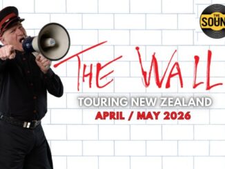 A man dressed in black with a red-trimmed cap shouts into a megaphone against a white brick wall, referencing Pink Floyd’s The Wall. Red graffiti-style text reads “The Wall,” with additional text promoting a New Zealand tour in April and May 2026.