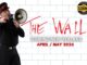 A man dressed in black with a red-trimmed cap shouts into a megaphone against a white brick wall, referencing Pink Floyd’s The Wall. Red graffiti-style text reads “The Wall,” with additional text promoting a New Zealand tour in April and May 2026.