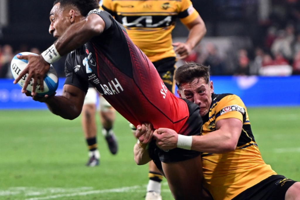 A Hurricanes player dives toward the try line while being tackled by a Crusaders defender during their Super Rugby Pacific match at One New Zealand Stadium in Christchurch.