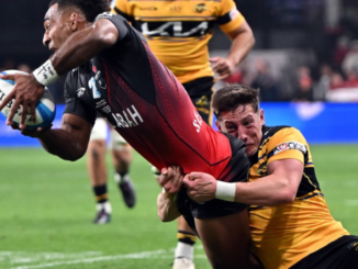 A Hurricanes player dives toward the try line while being tackled by a Crusaders defender during their Super Rugby Pacific match at One New Zealand Stadium in Christchurch.
