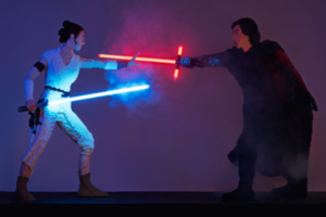 Alt text: Two LEGO-built Star Wars characters face off with glowing lightsabers, one blue and one red, posed mid-duel against a dark, smoky background.