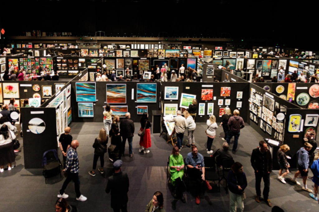 Visitors walk through rows of artwork displays at the NZ Art Show inside TSB Arena and Shed 6 in Wellington.