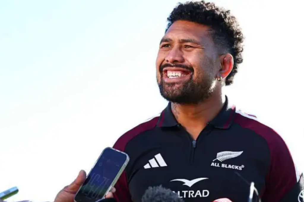 Ardie Savea smiles while speaking to reporters in All Blacks training gear.