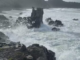 Large waves crash against rocks on a rugged Wellington region coastline during heavy swell conditions.
