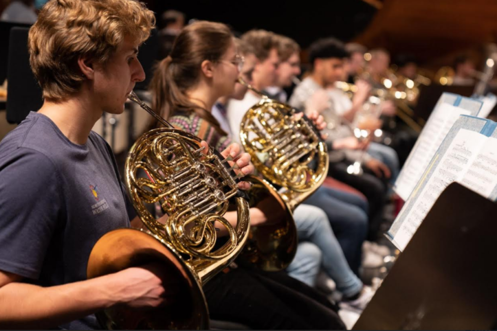 Members of the NZSO National Youth Orchestra rehearse with French horns and brass instruments ahead of their ocean-themed La Mer performances celebrating WWF-New Zealand's 50th anniversary.