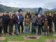 A group of Greater Wellington representatives, mana whenua, community members and volunteers gather beside a newly planted native tree at Queen Elizabeth Park.