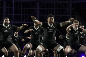 Alt text: All Blacks players perform the haka in black jerseys before a rugby match.