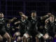 Alt text: All Blacks players perform the haka in black jerseys before a rugby match.