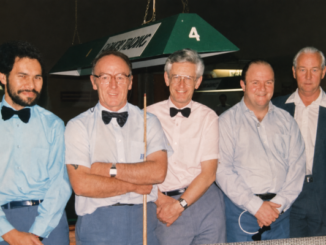 Russell Robinson, second from right, stands with four fellow billiards and snooker players beside a competition table.