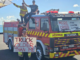 Firefighters stand on and beside an older fire engine holding signs about ageing appliances, health risks and the fire service crisis.