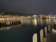 Wellington Harbour at night, with waterfront lights reflecting across the water and the city hills in the background.