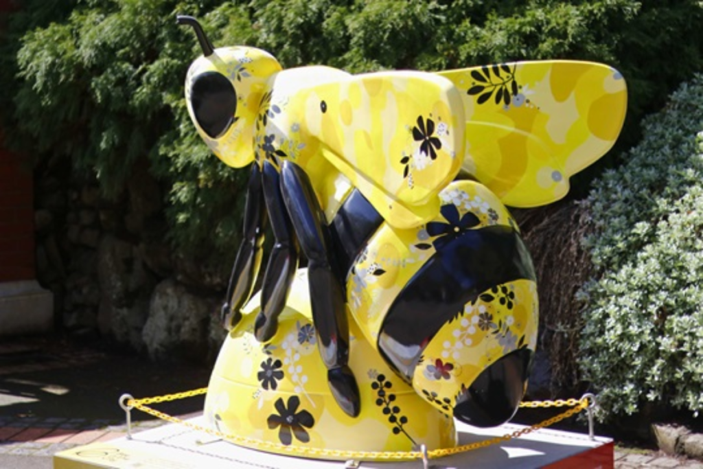 Yellow and black giant bee sculpture decorated with floral patterns in the Wellington Botanic Garden.