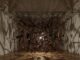 The remains of a garden shed suspended around a light in a gallery room, with the fragments casting long shadows across the walls.